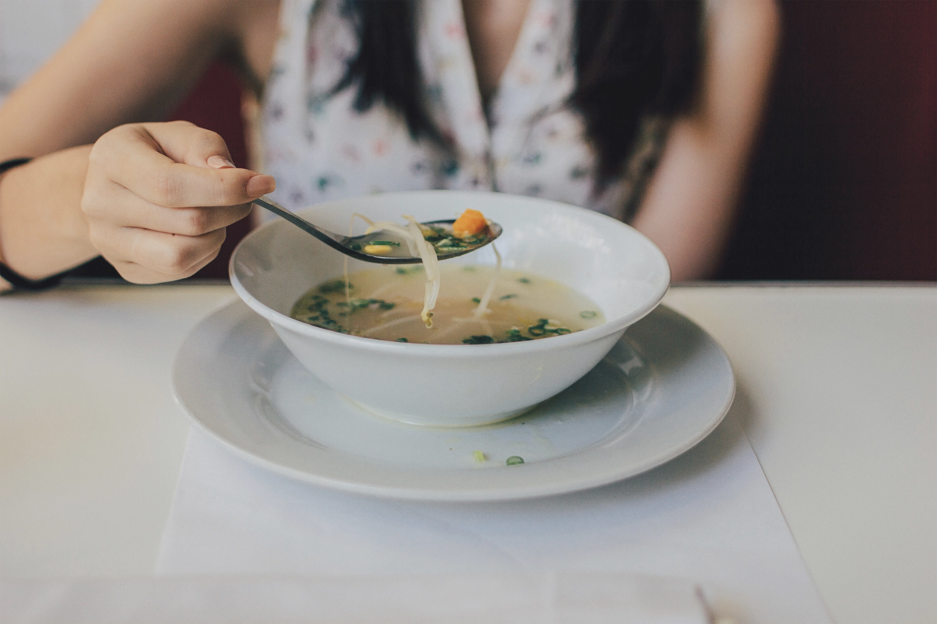 a person holding a spoon in a bowl of soup